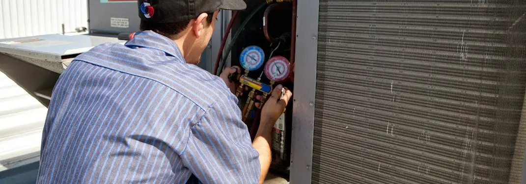 HVAC technician servicing a condenser unit in Pontotoc